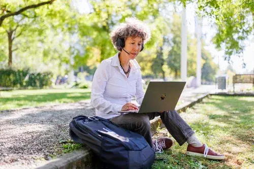 frau sitzt mit headset und laptop im freien frau sitzt mit headset und laptop im freien